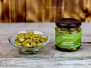 Borcan cu ardei Jalapeno feliat BIO Land.Luft, alături de o porție de rondele de ardei iute expuse într-un bol de sticlă pentru a evidenția textura și prospețimea.